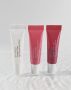 Drei Tuben KRX COSMETICS Pocket Filler Lip Plumping Gloss in den Farben Transparent, Rosé und Rot – auf glänzendem Hintergrund stehend.