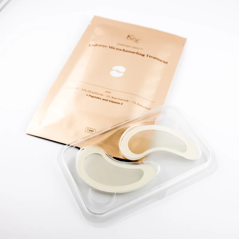 KrX Under-Eye Microneedling Treatment – goldene Einzelverpackung mit geöffnetem Tray und zwei transparenten Mikronadel-Patches in Augenform auf weißem Untergrund.