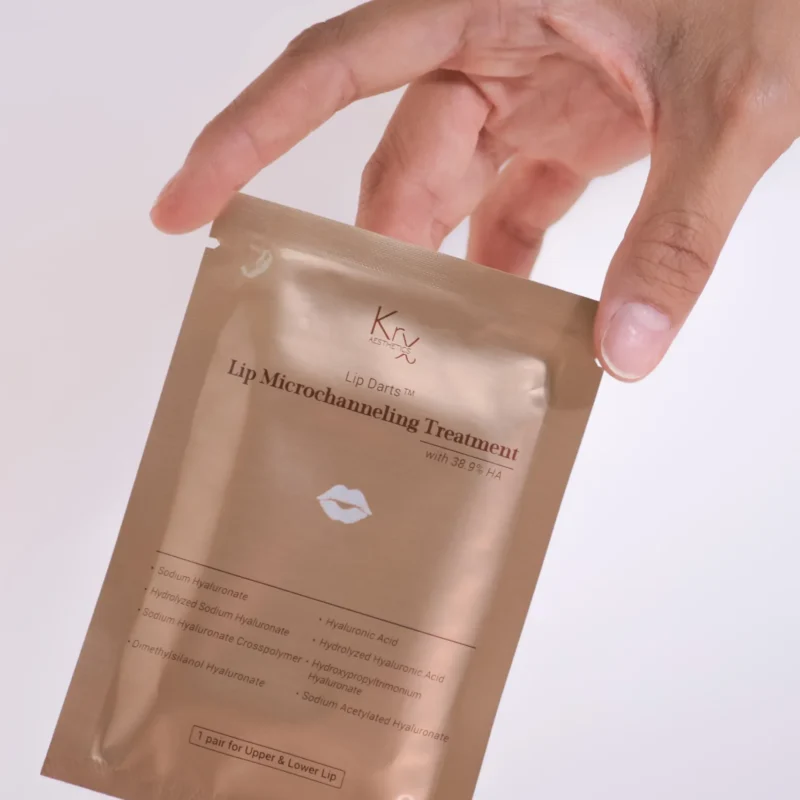 KrX Aesthetics Lip Microchanneling Treatment – goldene Einzelverpackung mit Lippenmotiv, gehalten von einer Hand, auf hellem Hintergrund.