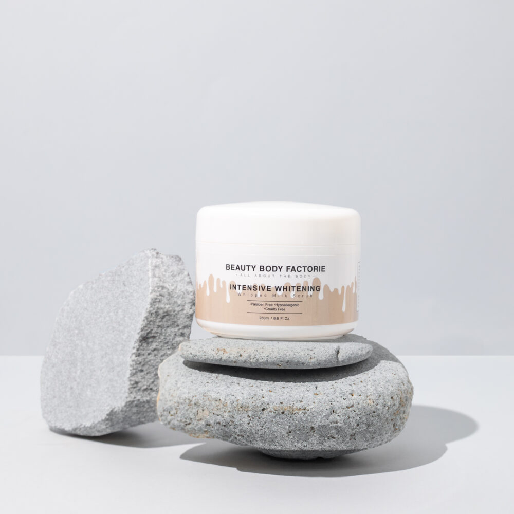 Intensiv aufhellendes Milch-Körperpeeling von Beauty Body Factorie auf grauen Steinen